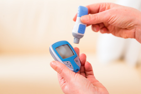 Woman with adult onset diabetes measuring blood sugar with indicator 