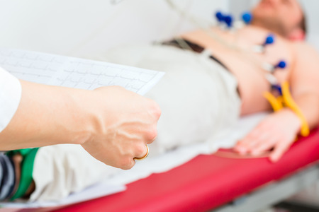 Female doctor analyzing ECG electrocardiogram of patient in hospitalの写真素材