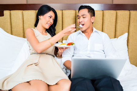 Couple sitting and eating in bedの写真素材