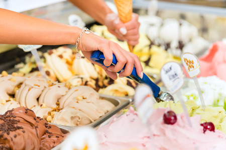 Young saleswoman in an ice cream parlor takes a scoop of ice cream
