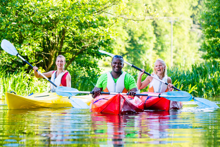 Friends paddling with canoe on forest riverの写真素材