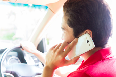 Asian young man telephoning with mobile phone or smartphone while driving car