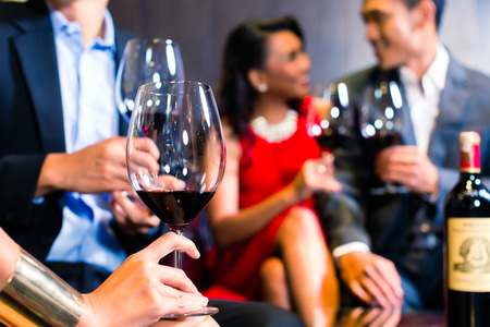 Close up of Asian friends chatting and drinking red wineの写真素材