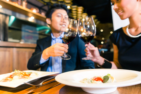 Elegant Asian couple toasting with red wineの写真素材