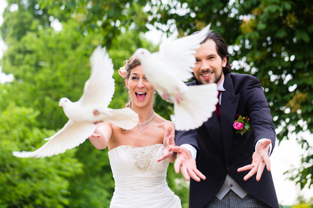 Bridal pair with flying white doves at weddingの写真素材