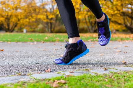 Woman sport running through autumn or fall park