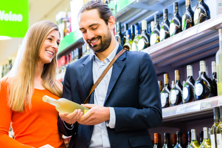Couple selecting wine in supermarketの写真素材