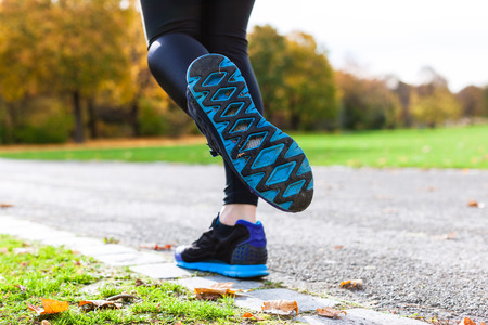 Woman sport running through autumn or fall park