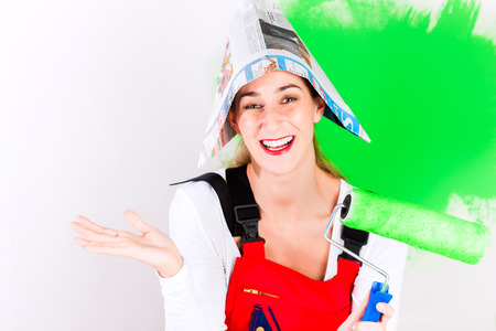Woman having fun at home improvement painting wall with green colour and brushの写真素材