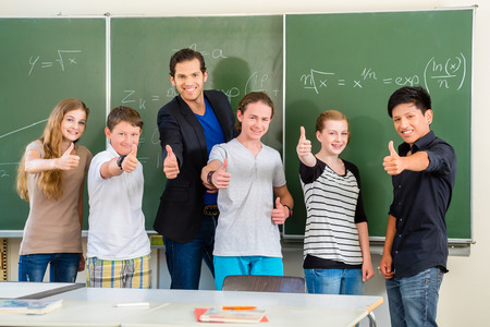 School and education - Teacher and students stand in front of a blackboard with math work in a classroom or classの写真素材