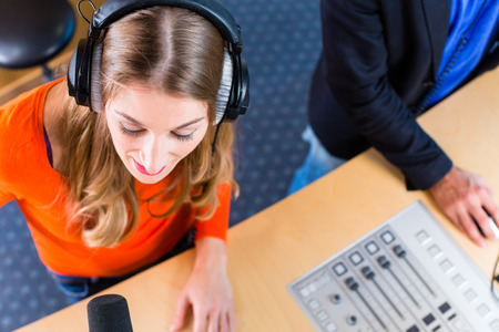 Presenters or moderators - man and woman - in radio station hosting show for radio live in Studio