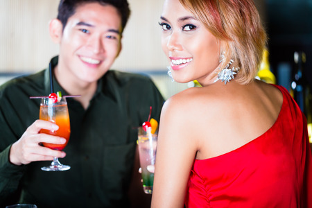Asian couple drinking cocktails in fancy barの写真素材