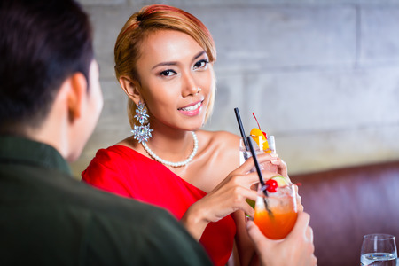 Asian couple drinking cocktails in fancy barの写真素材