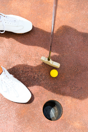 Woman playing miniature golf, holing inの写真素材