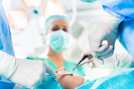 Hospital - surgery team in operating room or Op of a clinic operating on a patient in an emergency situationの写真素材