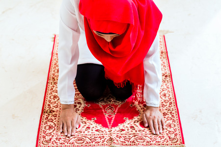 Asian Muslim woman praying with Quran and beads chain wearing traditional dressの写真素材
