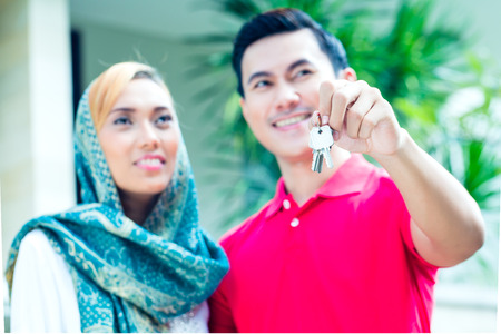 Asian Muslim man and woman moving into house presenting latchkey or key