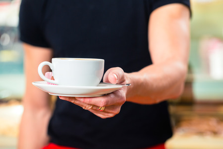 Waiter working in ice cream parlor or cafe serving coffeeの写真素材