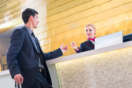 Man in Hotel check in at reception or front office being given key cardの写真素材