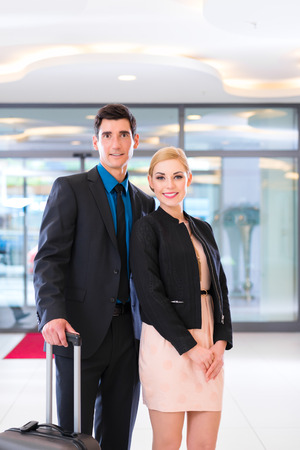 Man and woman arriving at hotel lobby with suitcaseの写真素材
