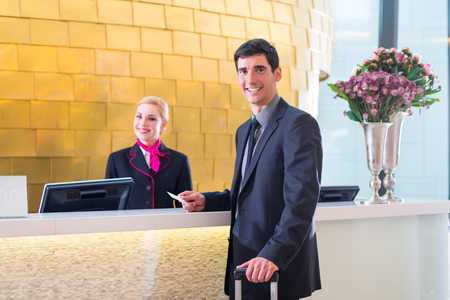 Man in Hotel check in at reception or front office being given key cardの写真素材