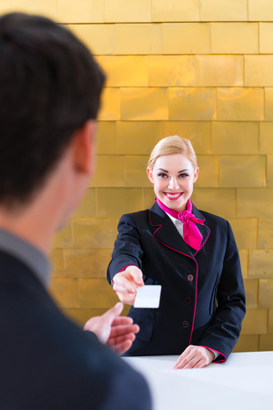 Man in Hotel check in at reception or front office being given key cardの写真素材