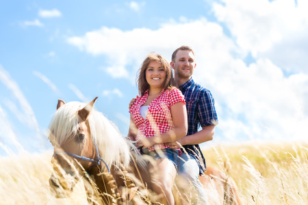 Couple riding on horse in summer meadowの写真素材