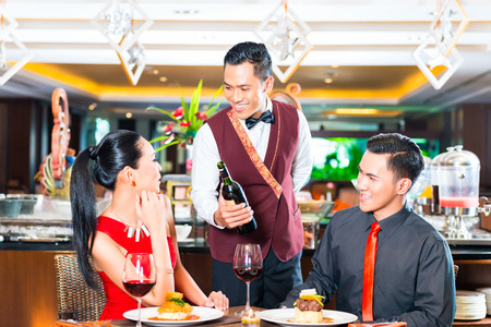 Waiter serving wine in Asian restaurantの写真素材