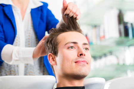 Female coiffeur washing men hair in hairdresser shopの写真素材