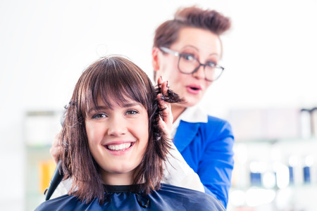 Female coiffeur blow dry women hair with blow dryer in shopの写真素材