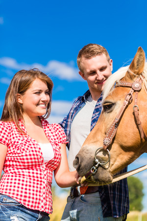 Couple petting horse on pony farmの写真素材