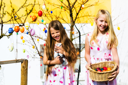 Little girls on an Easter Egg hunt on a meadow in spring, a child holds a living bunnyの写真素材