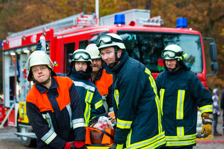 Accident - Fire brigade and Rescue team pulling cart with wounded person wearing a neck brace and...