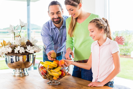 Mother, father, child picking fresh fruits for healthy living in home kitchenの写真素材