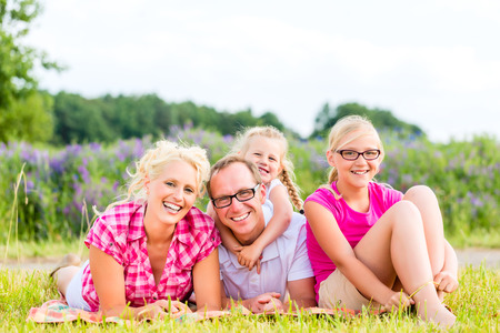 Family of Parents and daughters sitting on grass of lawn or fieldの写真素材