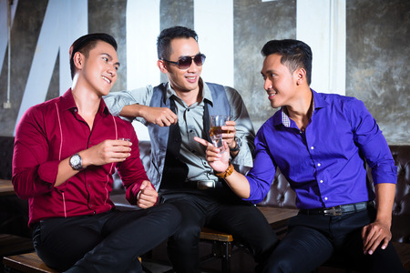 Asian party people man harass woman with her boyfriend in night club by inviting her to a drinkの写真素材