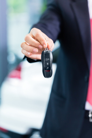 Car dealer handing over auto keyの写真素材