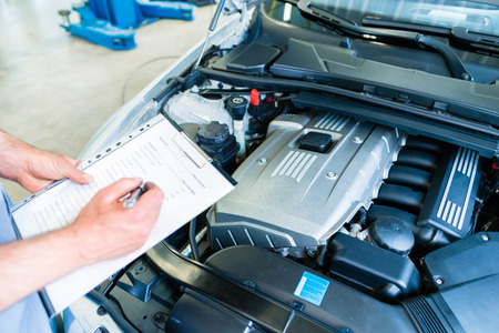 Auto mechanic controlling  car with checklist in workshop