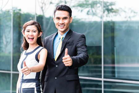 Asian business woman and man outside in front of buildingの写真素材