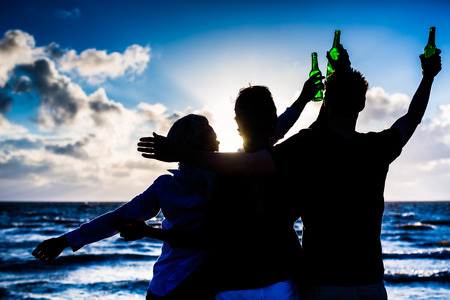 Friends enjoying bottled beer at sunset on German north sea beach