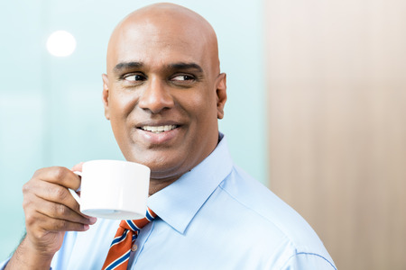 Indian Businessman with cup of coffee in officeの写真素材