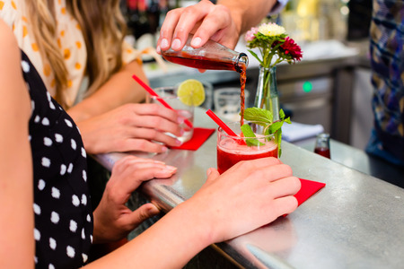 Two women friends in cafe bar drinking long drink or cocktails