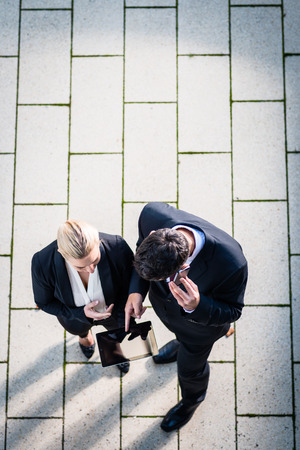 Business man and woman  with tablet computer standing on square, seen in top viewの写真素材