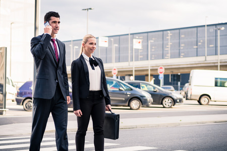 Business people at airport terminal travelling wearing briefcase and talking to smart phoneの写真素材