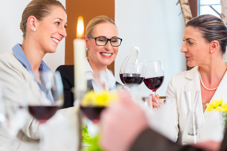 Group of men and women at business lunch in restaurant eating and drinkingの写真素材