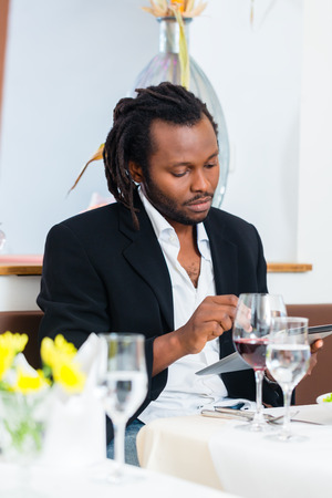 Business man, african american, with tablet in restaurant having lunch in restaurantの写真素材