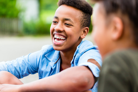 Siblings sitting on floor in yardの写真素材