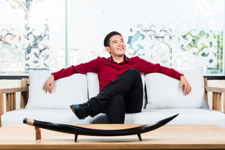 Asian Korean man sitting on sofa in furniture storeの写真素材