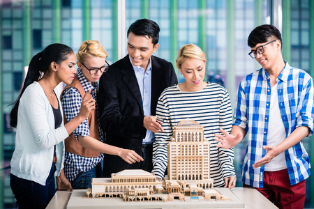 Team of architects presenting model building in presentation to customerの写真素材