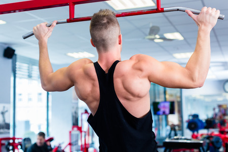 Man doing bodybuilding sport by exercising lifting dumbbells in fitness club or gym